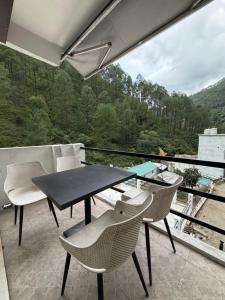 a patio with a table and chairs on a balcony at Chirag Homestay Kainchi in Nainital
