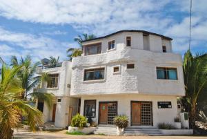 a white house with palm trees in front of it at Hostal Galapagos by Bar de Beto in Puerto Villamil