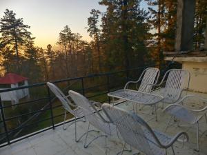 a group of chairs and tables on a balcony at Naqvi House in Murree