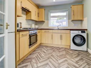 a kitchen with wooden cabinets and a washer and dryer at Dorset Escape in Gillingham