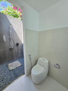 a bathroom with a toilet and a shower and a window at Piyo in Thoddoo