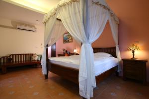 a bedroom with a canopy bed with curtains at Qian B&B in Jiamin