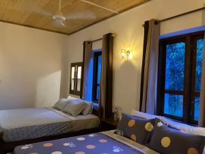 a bedroom with two beds and two windows at Aki Villa in Pasikuda