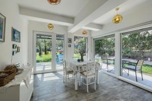 a dining room with a table and chairs and windows at Holiday House Altea in Banjole