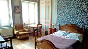 een slaapkamer met een bed, een stoel en een tafel bij Le Point du Jour in Revin