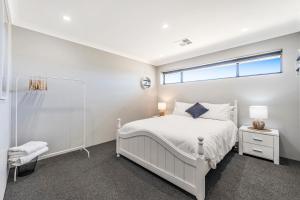 a white bedroom with a white bed and a window at Your Beach Getaway in Singleton