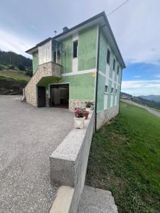 ein grün-weißes Gebäude am Straßenrand in der Unterkunft Casa Pasarón in Luarca