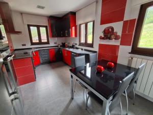 eine Küche mit roten Schränken und einem schwarzen Tisch mit Stühlen in der Unterkunft Casa Pasarón in Luarca