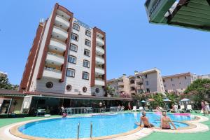 a hotel swimming pool with two women sitting next to a building at Golden Moon Apart Hotel in Kuşadası