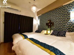 a bedroom with two beds and a cross on the wall at Alphabed松山城西 in Matsuyama