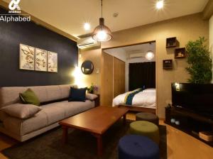 a living room with a couch and a bed at Alphabed松山城西 in Matsuyama