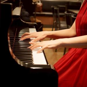 a woman in a red dress playing a piano at Hotel Sunroute Ginza in Tokyo