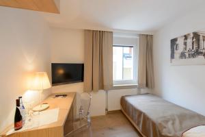 a hotel room with a bed and a desk and a window at Seehotel Schwan in Gmunden