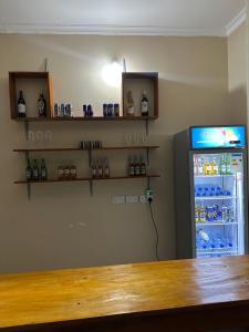 a room with a refrigerator and shelves with bottles at Ngara Sleasure in Songea