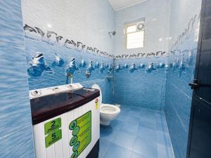 a bathroom with a toilet and penguins on the wall at Casafern Homestay Goa in Varca