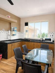 a kitchen with a glass table and chairs at Casafern Homestay Goa in Varca