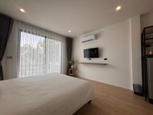 a bedroom with a white bed and a window at The Hidden Place Bangtao in Bang Tao Beach