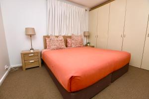 a bedroom with a bed with orange sheets and pink pillows at Goldsbrough 2 bedrooms split apartment in Sydney