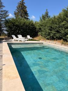 a swimming pool with two chairs and a table at Gite Le Mas Rigal in Saint-Amans-des-Cots