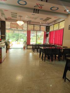 a dining room with tables and chairs and red curtains at Hotel Shyam Vandan in Rīngas