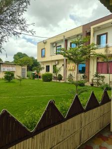 a fence in front of a building with a yard at Hotel Shyam Vandan in Rīngas
