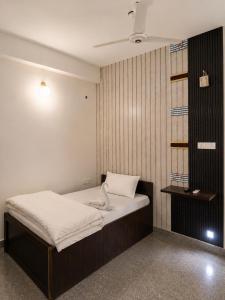 a small bedroom with a bed with white sheets at White Lily in Guwahati