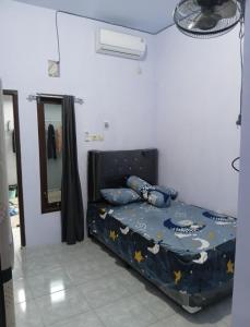 a bedroom with a bed with a comforter and a mirror at DMP Homestay in Ketapang
