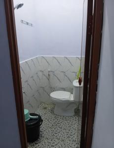 a bathroom with a toilet and a tiled floor at DMP Homestay in Ketapang