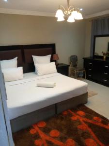 a bedroom with a large white bed with a mirror at Munjiz Lodge in Livingstone