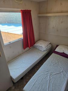 two beds in a room with a window at Le bungalow des champs in Saint-Georges-de-Reintembault