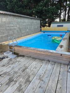 a pool with a wooden deck and a swimming pool with at Le bungalow des champs in Saint-Georges-de-Reintembault +7 photos