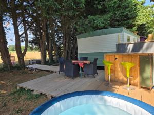 a wooden deck with a table and chairs at Le bungalow des champs in Saint-Georges-de-Reintembault