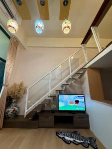 a living room with a staircase with a flat screen tv at 山下溫泉民宿 in Yü-shih-ts'un