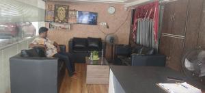 a man sitting on a couch in a living room at HoTEL RAJ VIHAR RESIDENCY in Vijayawāda