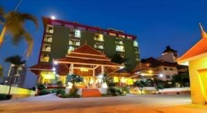 a large green building at night with palm trees at Phuphaya Resort Pattaya in Pattaya South