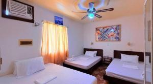 a room with two beds and a ceiling fan at Cocomango's Resort in Taporok