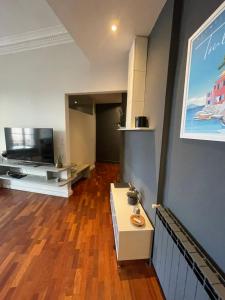 a living room with a wooden floor and a television at La Perle de Toulon, grand appartement tout confort, idéalement situé in Toulon