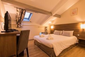 a bedroom with a bed and a desk and a television at La Bastide de Sanilhac in Sanilhac