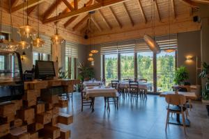 a restaurant with tables and chairs and large windows at Ura e Kovacit Resort & Agrotourism in Voskopojë