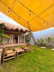 a patio with tables and chairs under a large umbrella at Alfa Kuta in Kuta Lombok