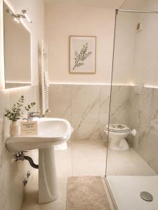 a white bathroom with a sink and a toilet at Appartamento Magnolia 209 in Pomezia +10 photos