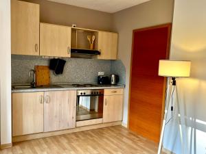 a kitchen with wooden cabinets and a stove top oven at Appartement Mari Lou in Ebermannstadt