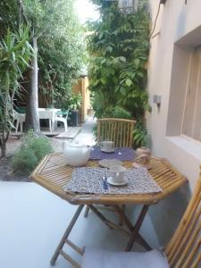 a wooden table with cups and saucers on a patio at Clos Réginel Remparts Sud in Avignon