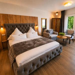 a bedroom with a large bed and a chair at Hotel am Kurpark in Bad Lauterberg