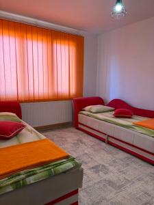 two beds in a room with red and orange curtains at Stan na dan in Pljevlja