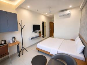 a bedroom with a bed and a desk and a tv at hotel green rio in Ahmedabad +18 photos
