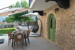 a patio with a table and chairs and a green door at Dervisia Stonehouse 3 in Lazaráta +36 photos