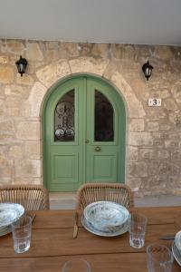 a green door with two chairs and a table with plates at Dervisia Stonehouse 3 in Lazaráta