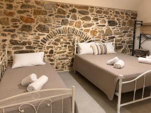 two beds in a room with a stone wall at Mastic Ev in Chios