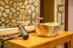 a wooden bowl on a wooden counter with a hammer at Equator Lodge & Campsite in Kikorongo +267 photos